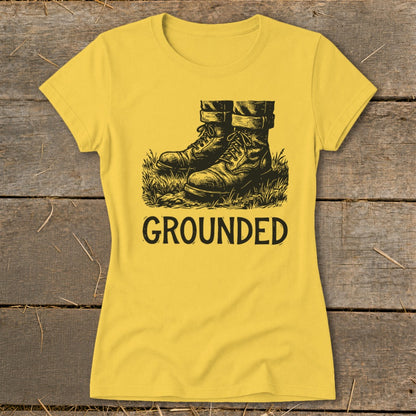 Yellow t-shirt with black graphic of boots in grass and the word "GROUNDED".