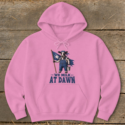 Pink hoodie with cartoon cow holding flag and text "We Milk At Dawn".