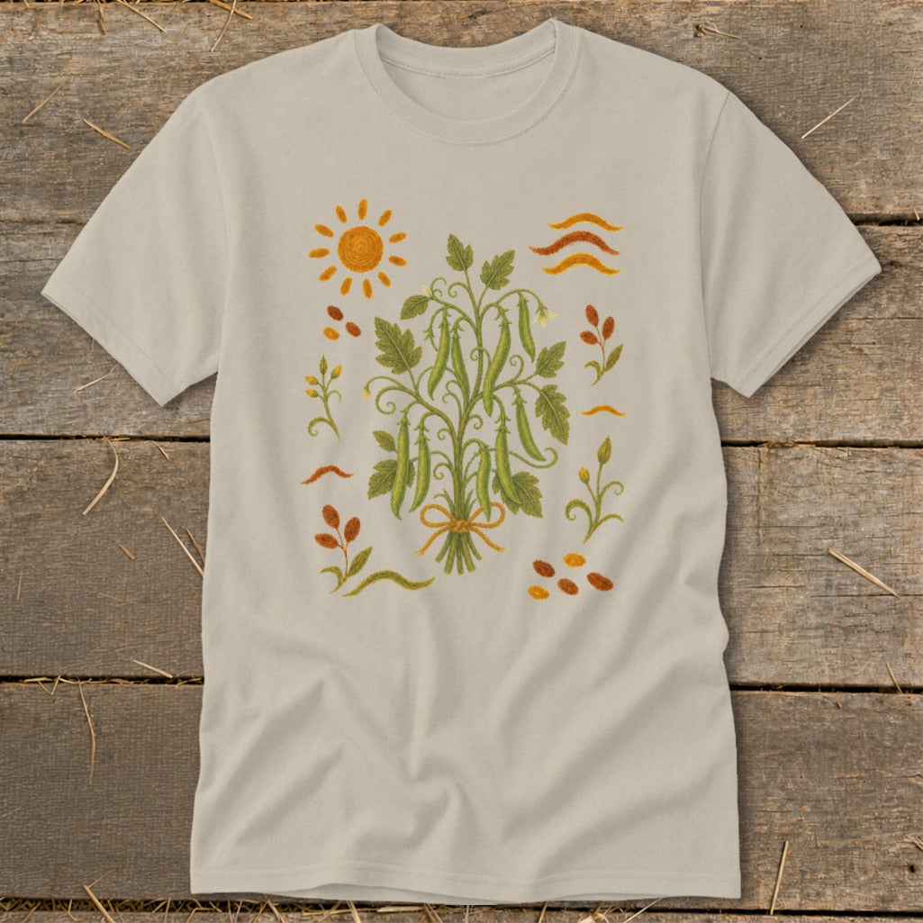 T-shirt with embroidered peas, sun, and scattered leaves and seeds.