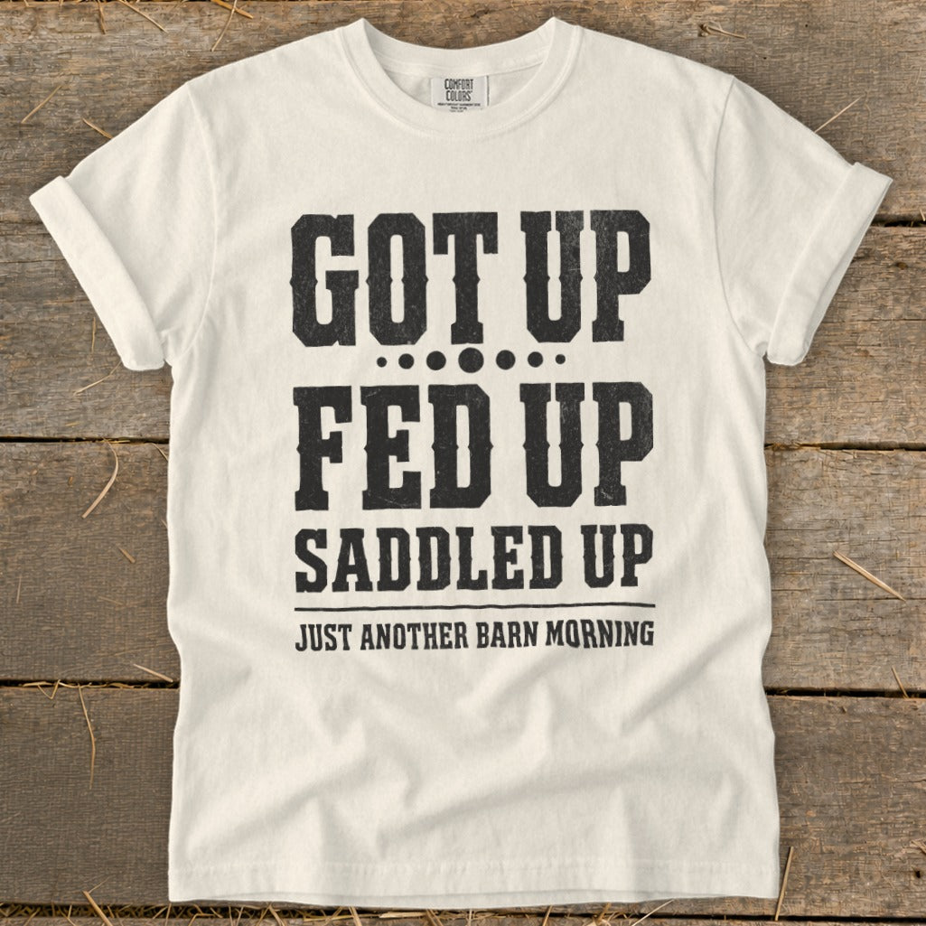 White t-shirt with black text: "GOT UP FED UP SADDLED UP JUST ANOTHER BARN MORNING"