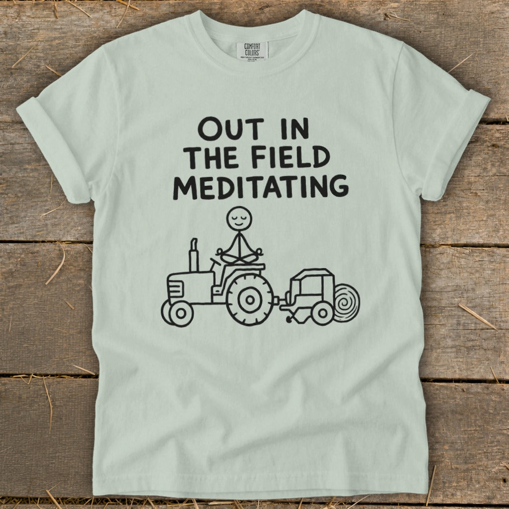 Light green t-shirt with "OUT IN THE FIELD MEDITATING" and stick figure meditating on tractor.