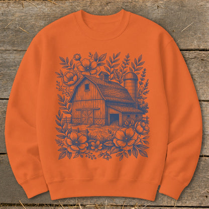 Orange sweatshirt with a navy blue barn and floral illustration.