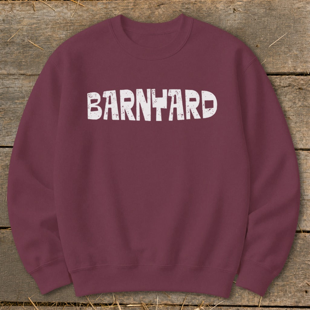 Maroon crewneck sweatshirt featuring the distressed white text BARNYARD centered across the chest, laid on a wooden background.