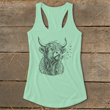 Highland cow with eyes closed blows on a dandelion on a mint green tank top.