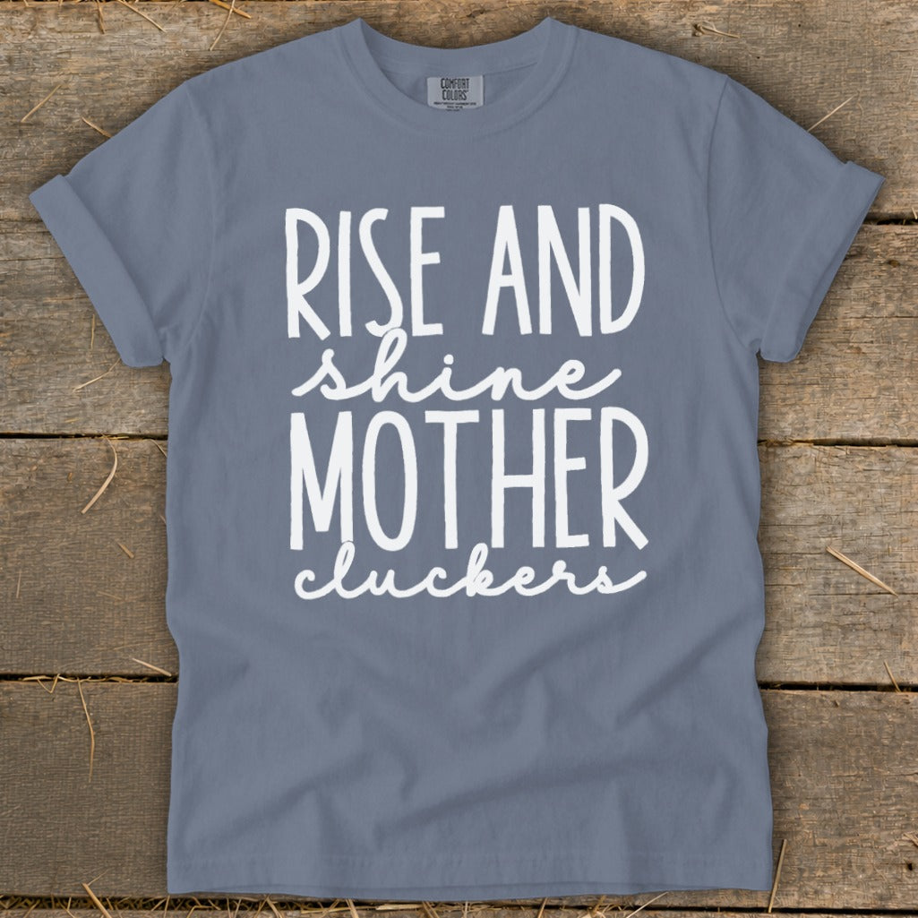 Blue t-shirt with white text: "Rise and shine mother cluckers"
