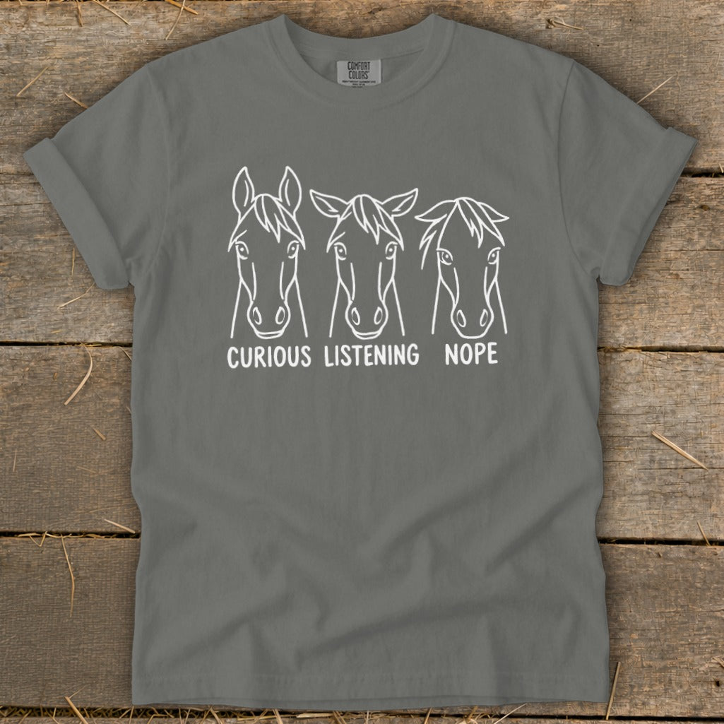 A dark grey t-shirt featuring three horse face line drawings with captions reading curious, listening, and nope.