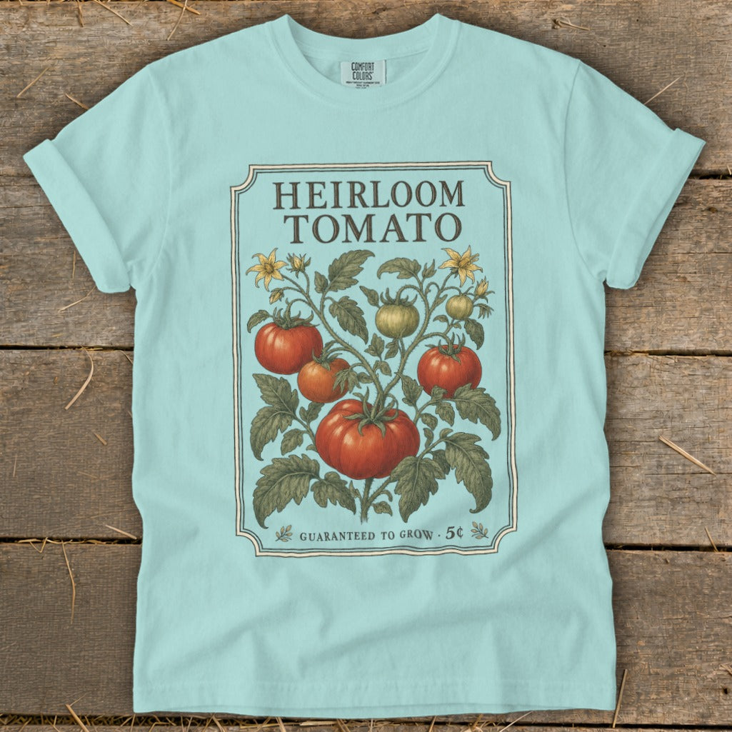 Light blue t-shirt featuring "Heirloom Tomato" text and vintage tomato plant illustration.