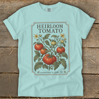 Light blue t-shirt featuring "Heirloom Tomato" text and vintage tomato plant illustration.