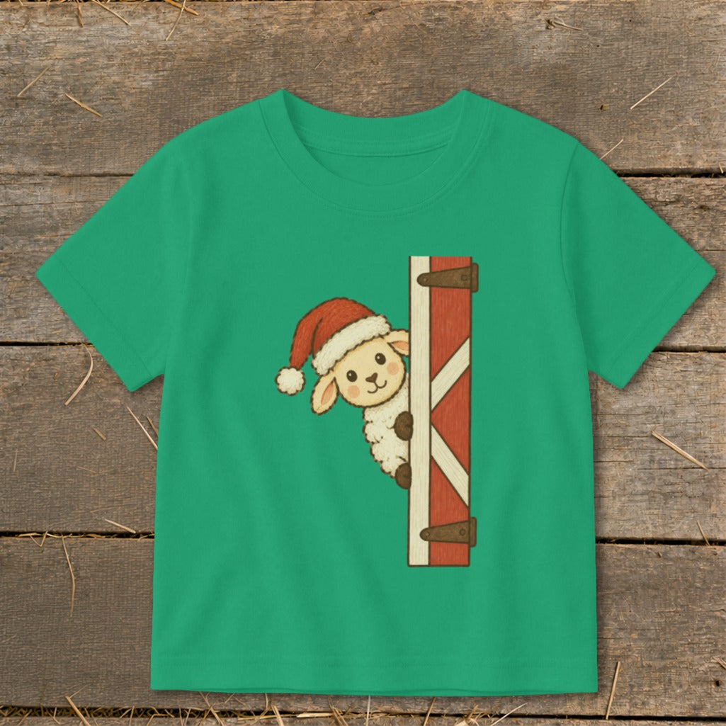 Green t-shirt with a drawing of a sheep wearing a Santa hat peeking from behind a barn door.