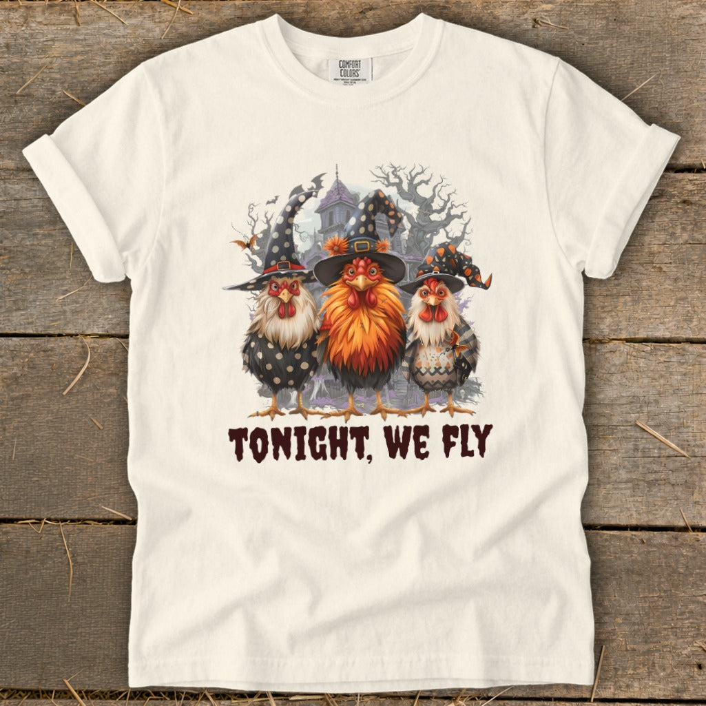 Three chickens in witch hats stand in front of a spooky house with the text "TONIGHT, WE FLY."