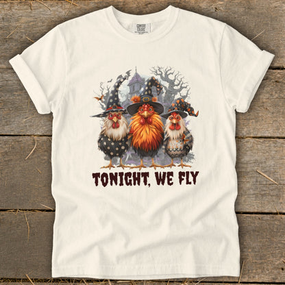 Three chickens in witch hats stand in front of a spooky house with the text "TONIGHT, WE FLY."
