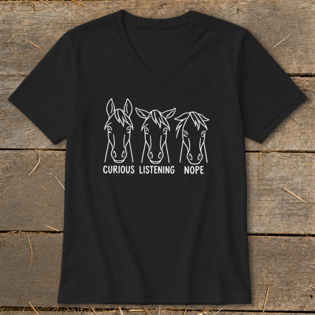 A black V-neck t-shirt featuring a white graphic of three horse heads with the captions curious, listening, and nope.