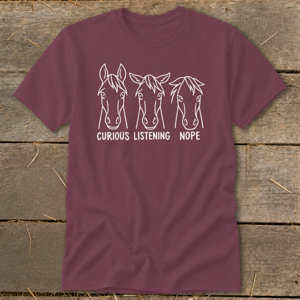 Maroon t-shirt featuring three horse heads with varying ear positions labeled curious, listening, and nope.