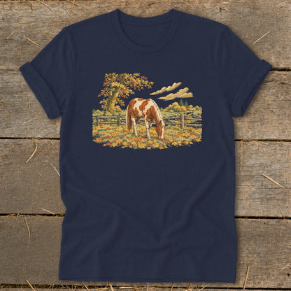 Horse grazing in autumn field with colorful leaves and wooden fence.