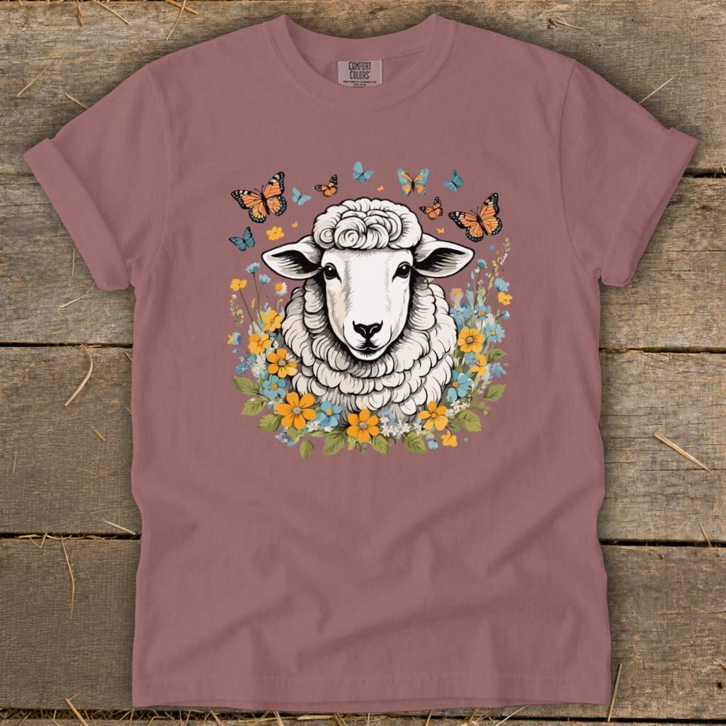 T-shirt with a white sheep surrounded by butterflies and colorful flowers.
