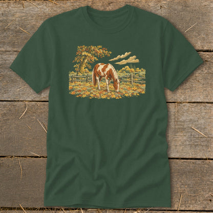 Green t-shirt with a graphic of a brown and white horse grazing in autumn leaves.