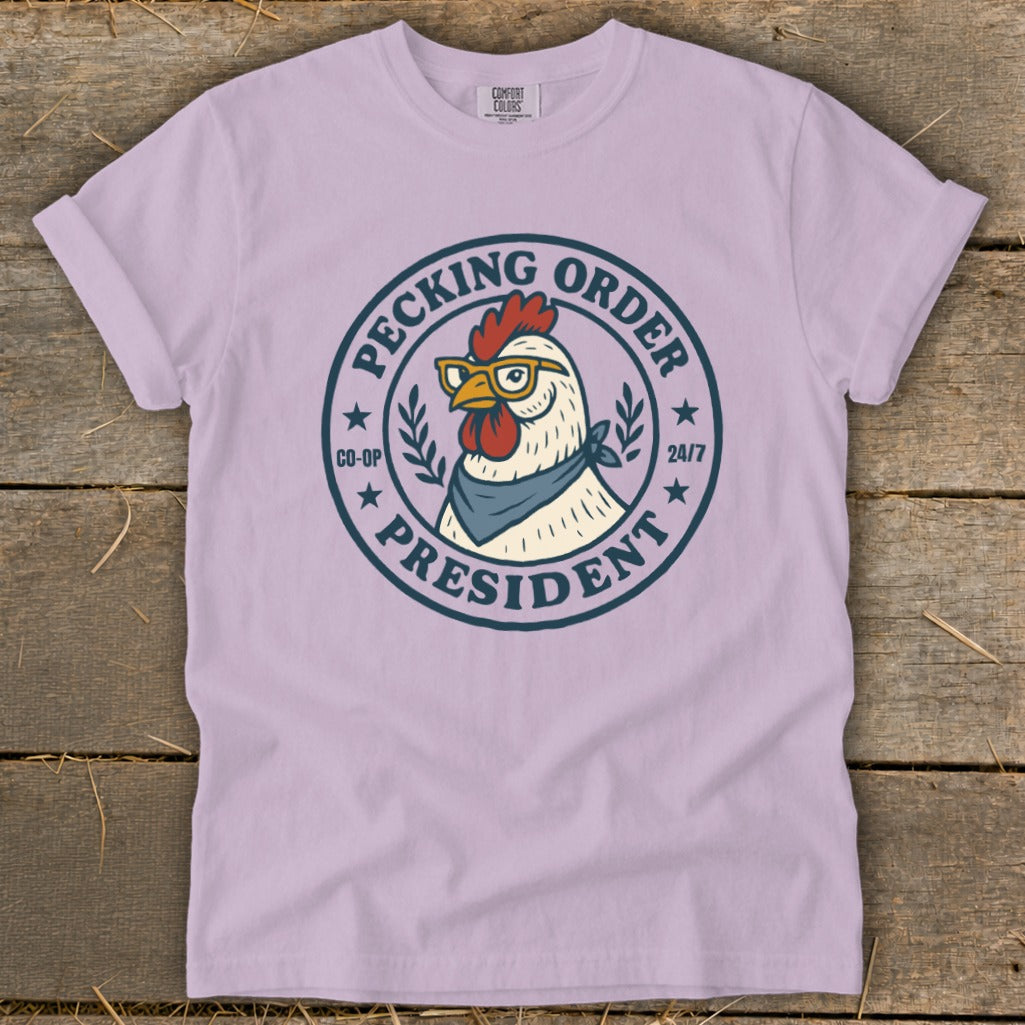 Lavender t-shirt with a chicken wearing glasses and a bandana, with "Pecking Order President" text.