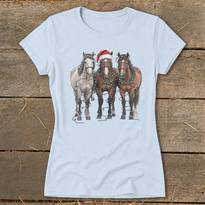 Three horses adorned with Christmas lights and a Santa hat on a light blue t-shirt.
