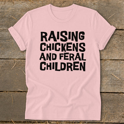 Pink t-shirt with black text reading "RAISING CHICKENS AND FERAL CHILDREN."