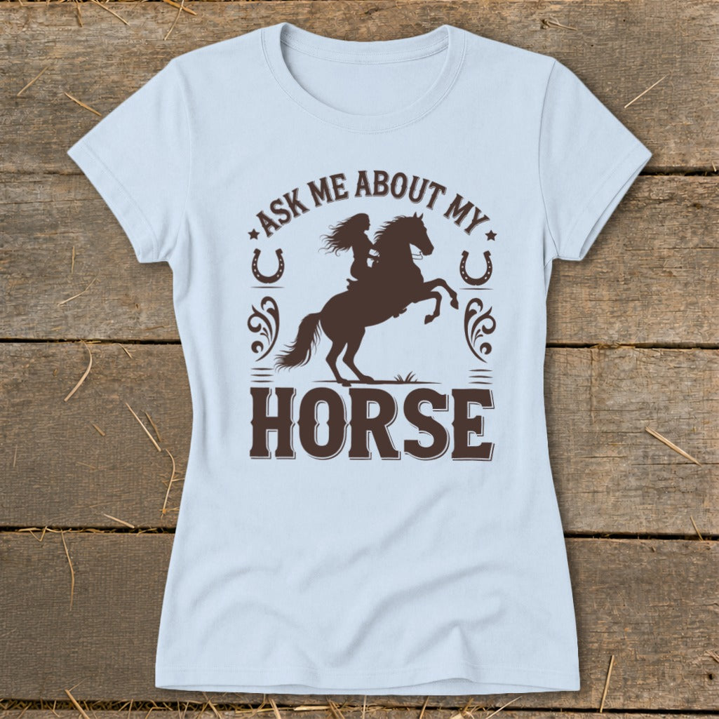 Light blue t-shirt with brown graphic of a woman riding a horse and text "ASK ME ABOUT MY HORSE".