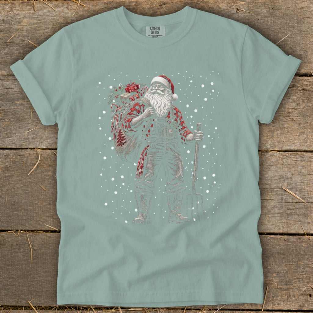 Santa in overalls with a sack of gifts and pitchfork, amidst falling snow.