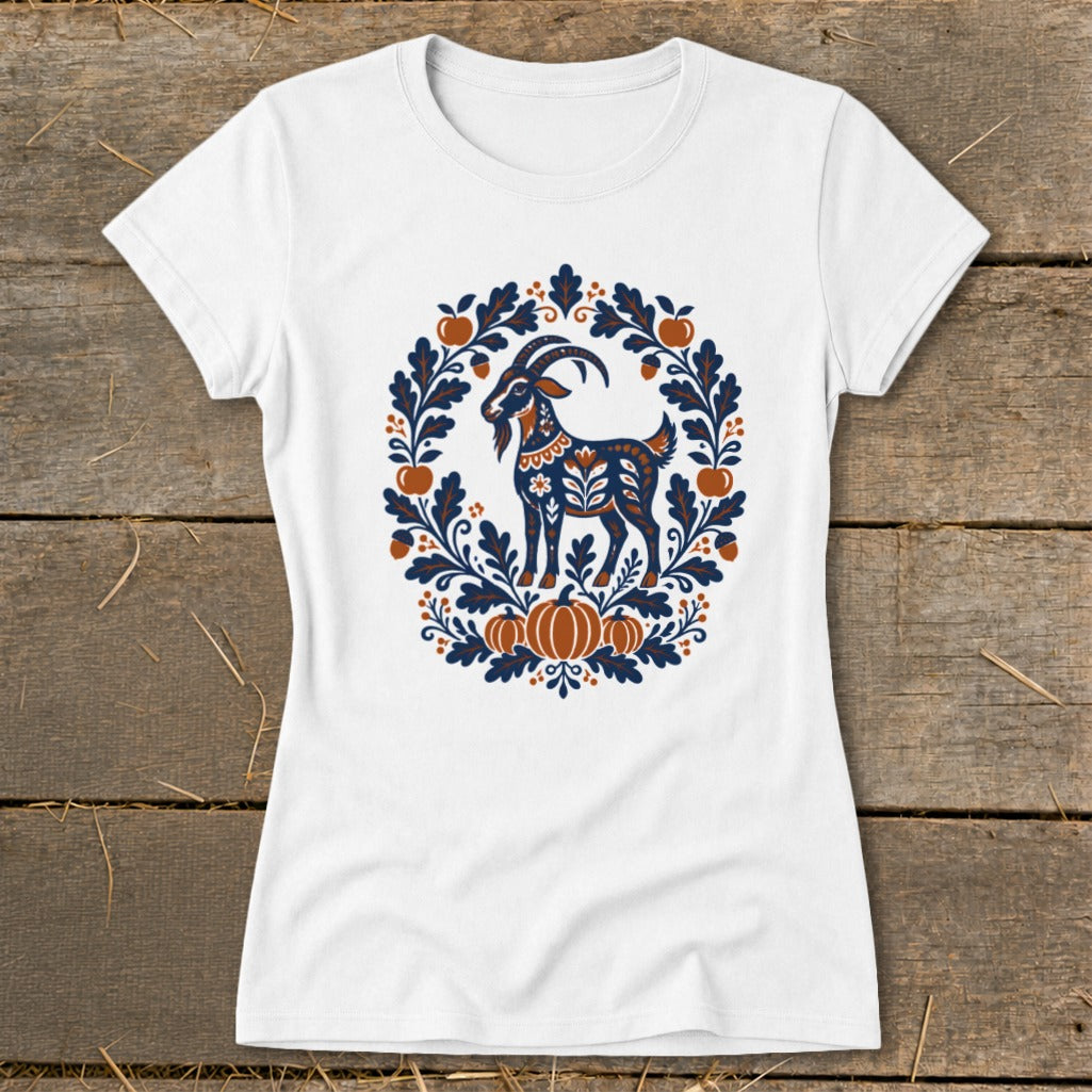 A white t-shirt featuring a folk art graphic of a goat surrounded by autumn leaves and pumpkins.
