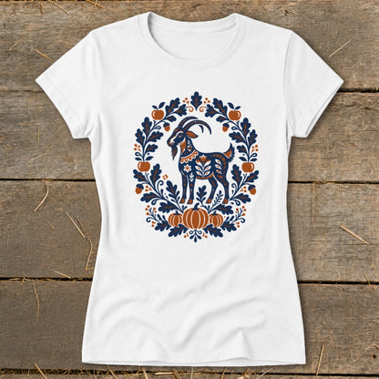 A white t-shirt featuring a folk art graphic of a goat surrounded by autumn leaves and pumpkins.