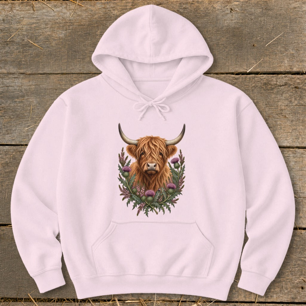Light pink hoodie with a Highland cow illustration surrounded by thistles.