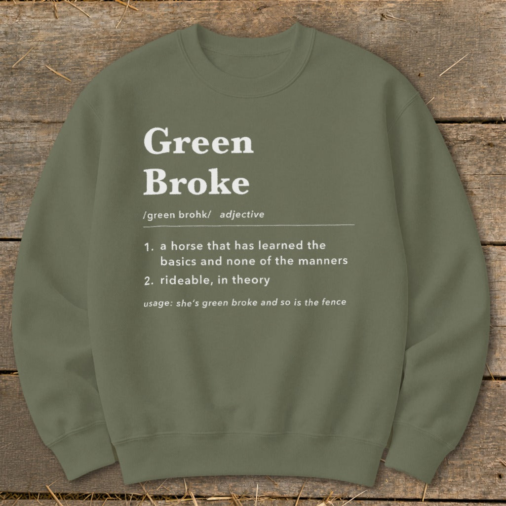Olive green crewneck sweatshirt featuring white dictionary-style text defining Green Broke on a rustic wooden background.