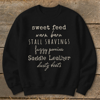 Black sweatshirt with white text: sweet feed, warm barn, stall shavings, fuzzy ponies, saddle leather, dusty boots.
