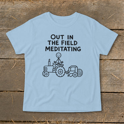 Light blue t-shirt with "Out in the Field Meditating" text and stick figure on tractor graphic.