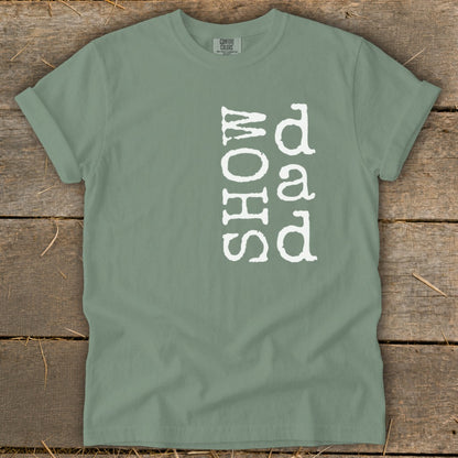 Sage green t-shirt with vertical white text "SHOW dad" on the front.