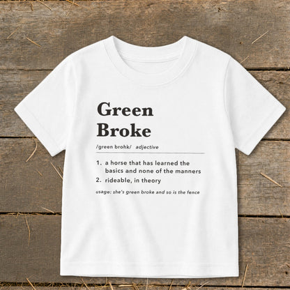 White t-shirt featuring black dictionary-style text defining Green Broke laid on wooden background.