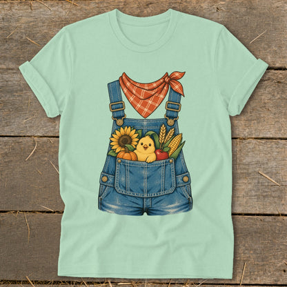 Light mint green t-shirt with denim overalls pocket graphic featuring a chick, sunflower, pumpkin, corn, and apple.