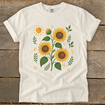 White t-shirt with a print of three sunflowers, a sun, and leaves.