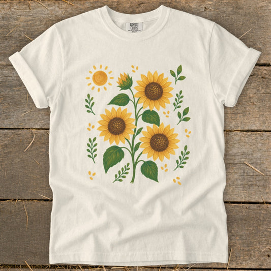 White t-shirt with a print of three sunflowers, a sun, and leaves.