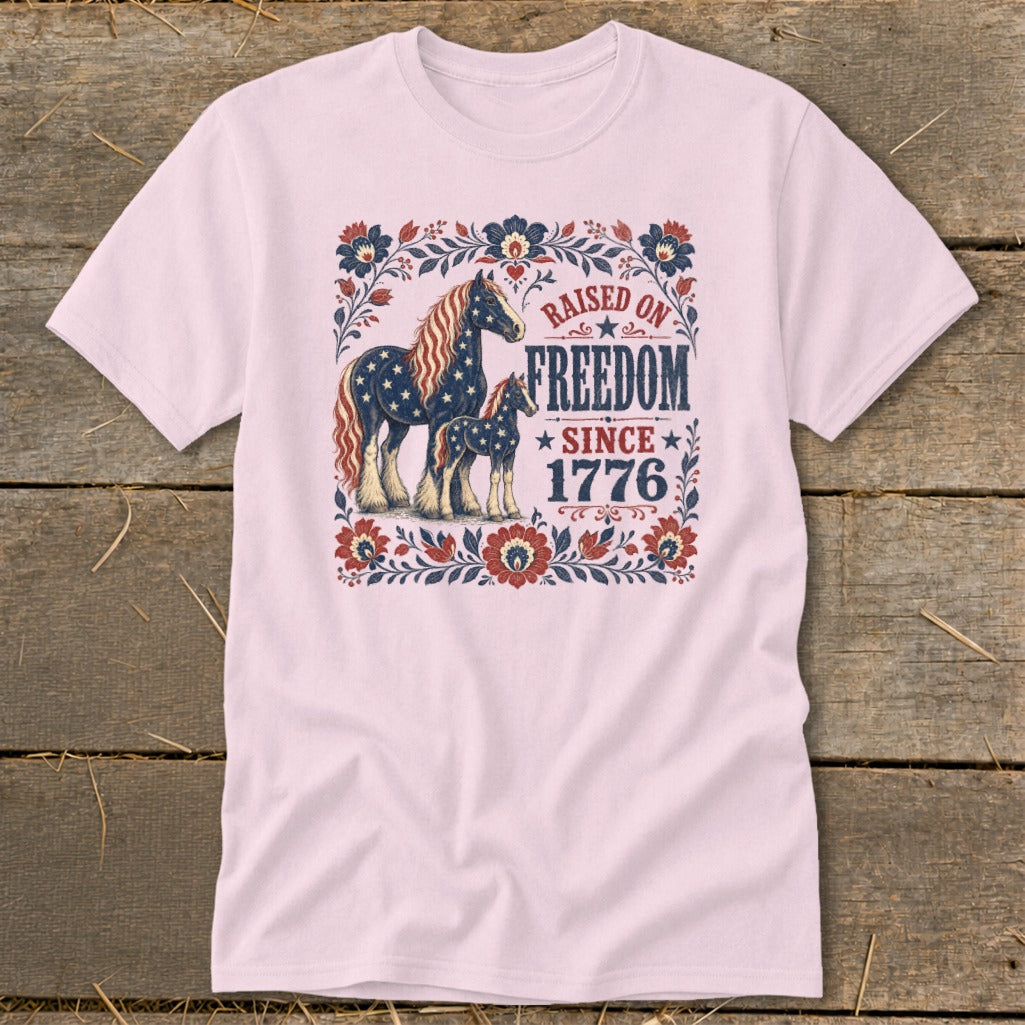 Light pink t-shirt with horses and "Raised on Freedom Since 1776" text.