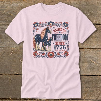 Light pink t-shirt with horses and "Raised on Freedom Since 1776" text.