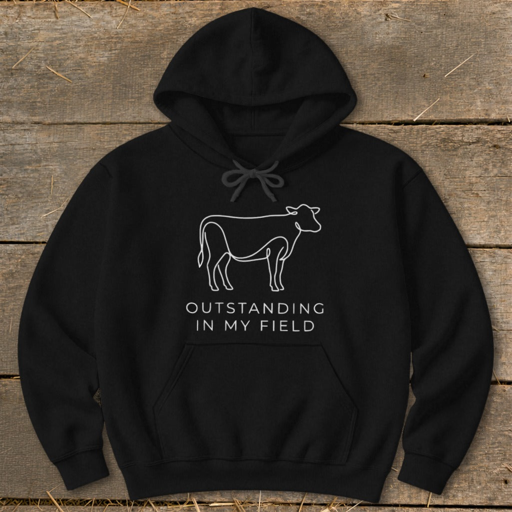 Black hoodie with a white line drawing of a cow and text "Outstanding in my field."