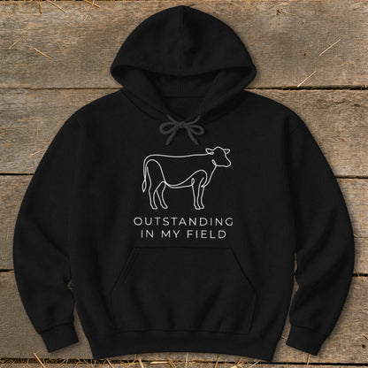 Black hoodie with a white line drawing of a cow and text "Outstanding in my field."