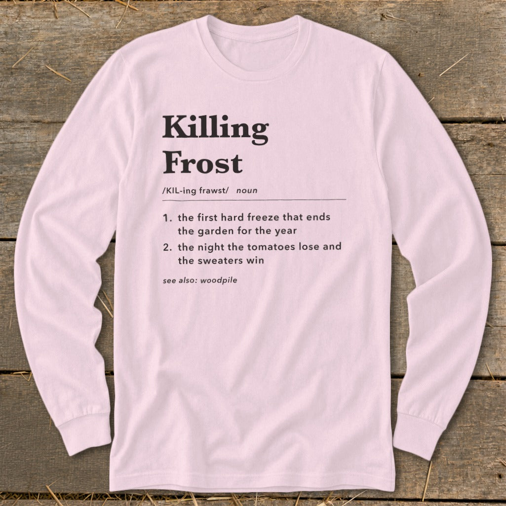 A light pink long-sleeve t-shirt with black text defining the term Killing Frost laid flat on wooden planks.