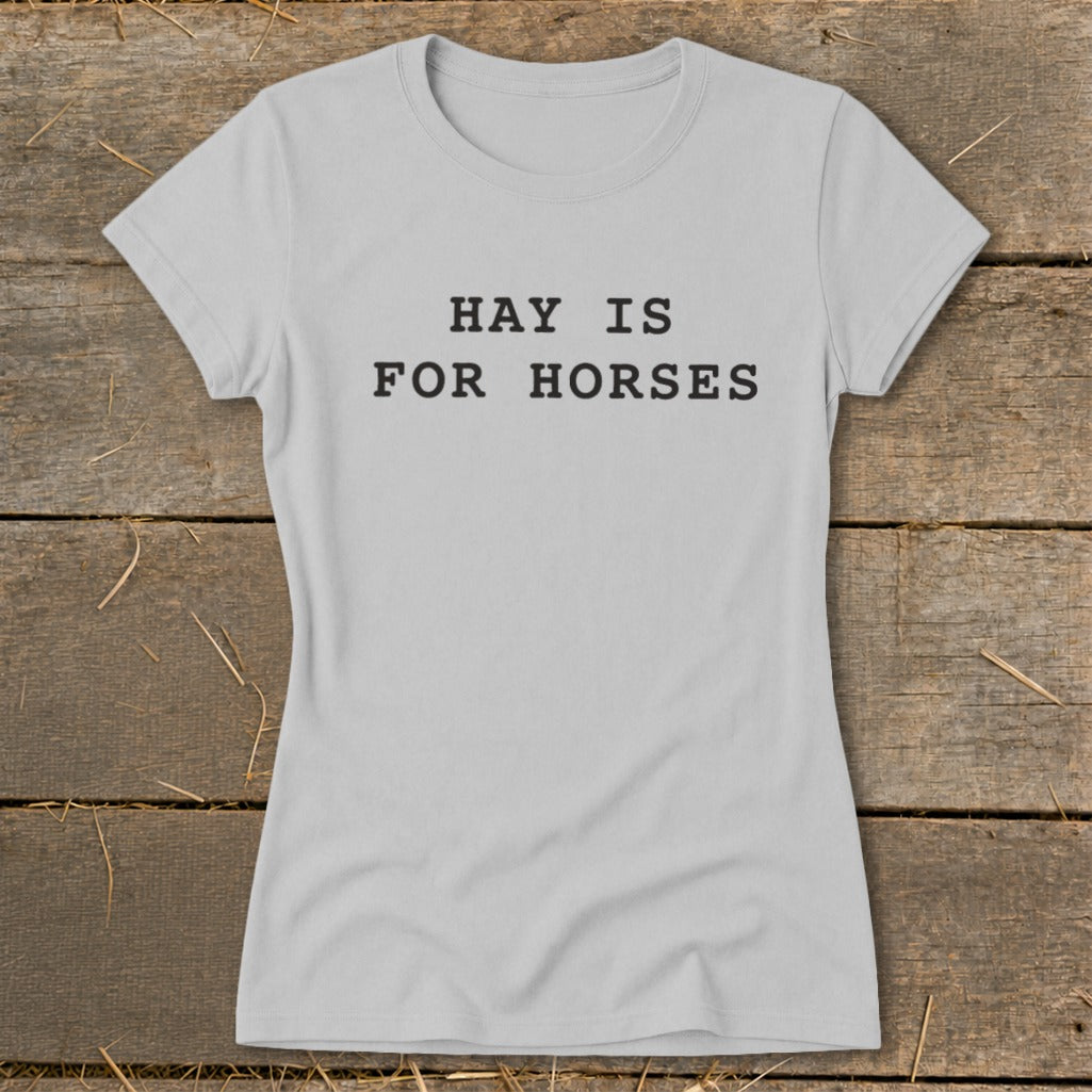 Grey t-shirt with black text "HAY IS FOR HORSES" on rustic wood background.