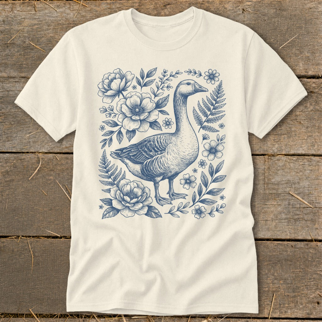 Cream t-shirt with a blue ink sketch of a goose surrounded by flowers and foliage.