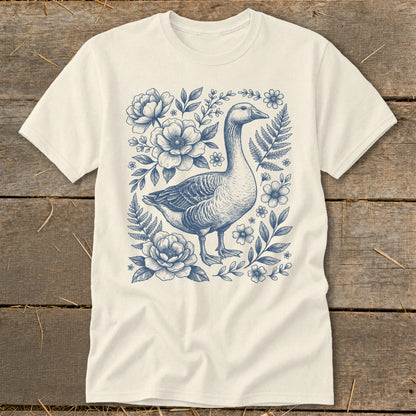 Cream t-shirt with a blue ink sketch of a goose surrounded by flowers and foliage.