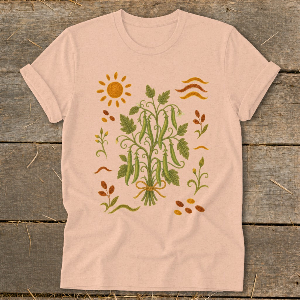 Peach t-shirt with a graphic of a pea plant surrounded by sun and leaves.