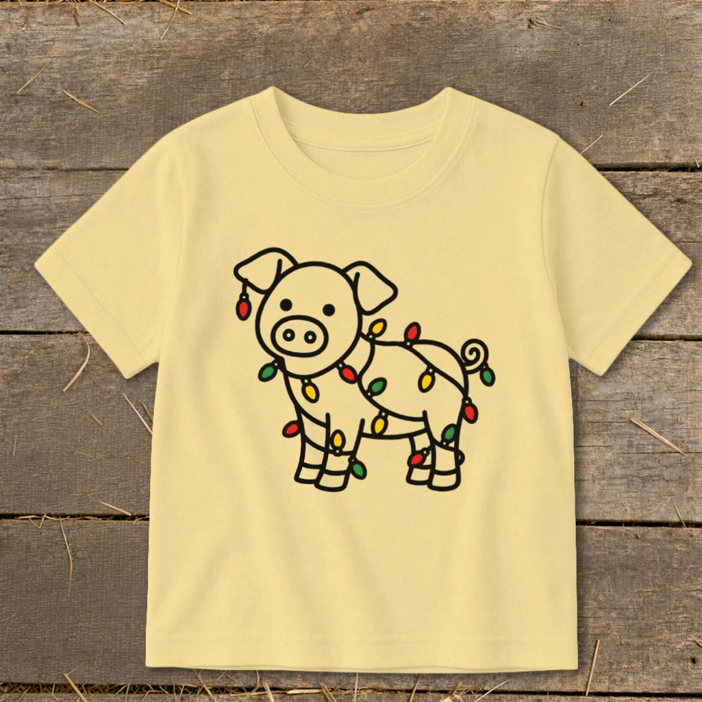 Light yellow short-sleeved children's t-shirt featuring a black outline graphic of a pig wrapped in Christmas lights.