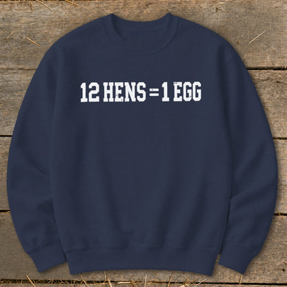 Dark blue crewneck sweatshirt featuring the white distressed text 12 HENS = 1 EGG on the chest, laid flat on wooden planks.