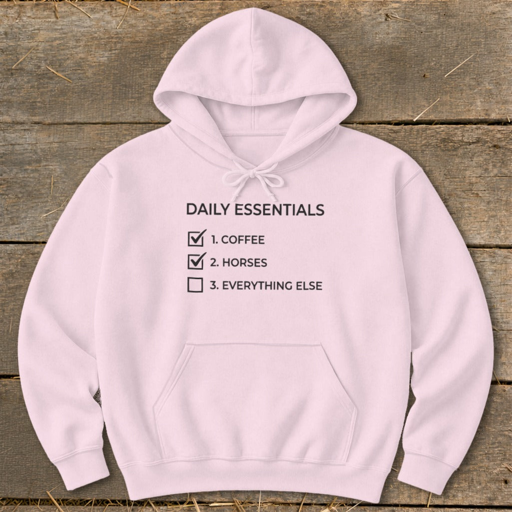 Light pink hoodie with "Daily Essentials" text and checklist for coffee and horses.