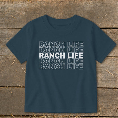 Dark blue t-shirt featuring the stacked white text Ranch Life laid flat on wooden boards.