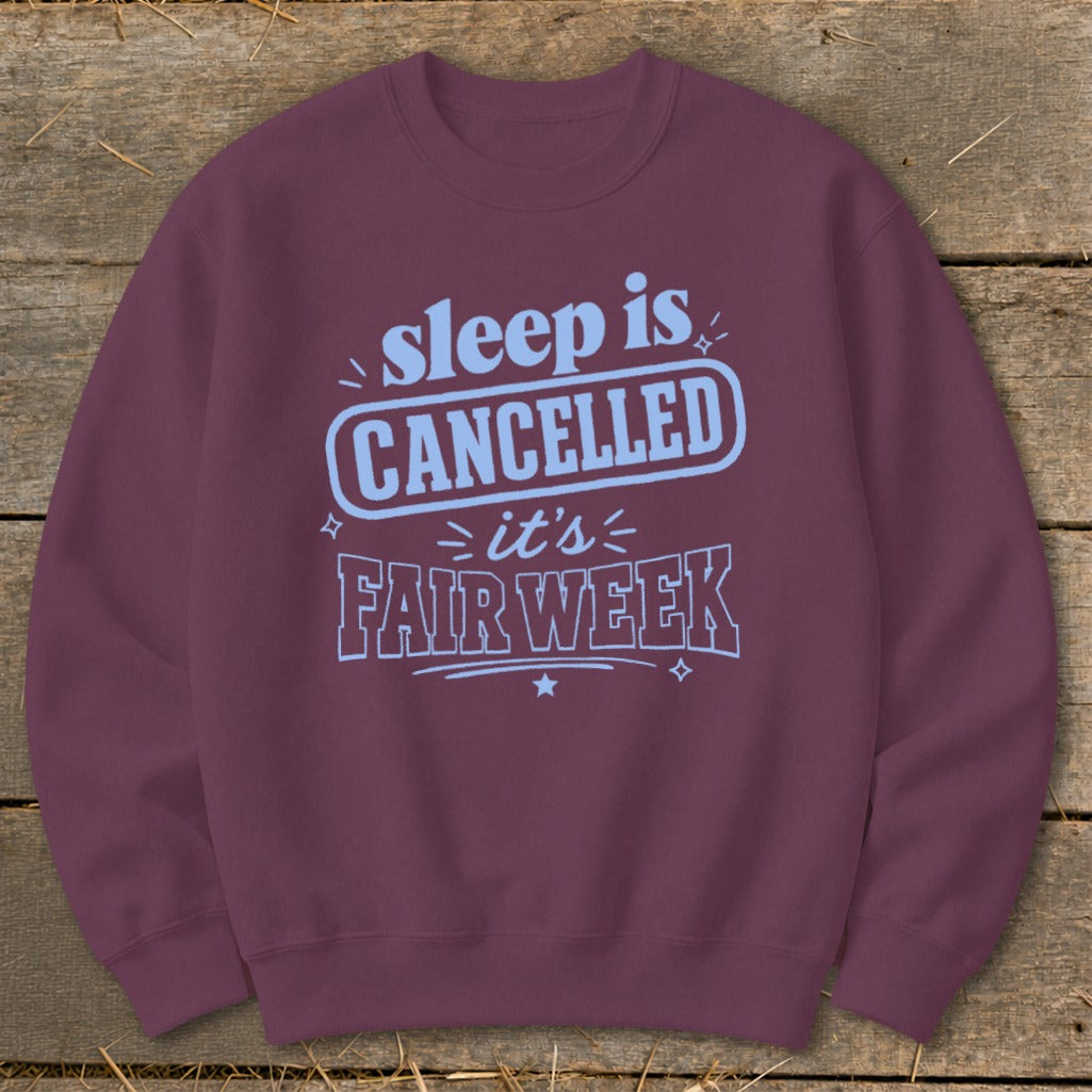 Maroon sweatshirt with light blue text "sleep is CANCELLED it's FAIR WEEK".
